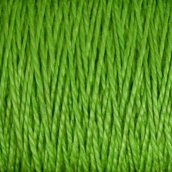 Close-up image of 5/2 Pearl Cotton Yarn by Supreme Corp. The versatile yarn strands are neatly aligned and tightly wound on a large cone, showcasing a vibrant, uniform green color and texture.