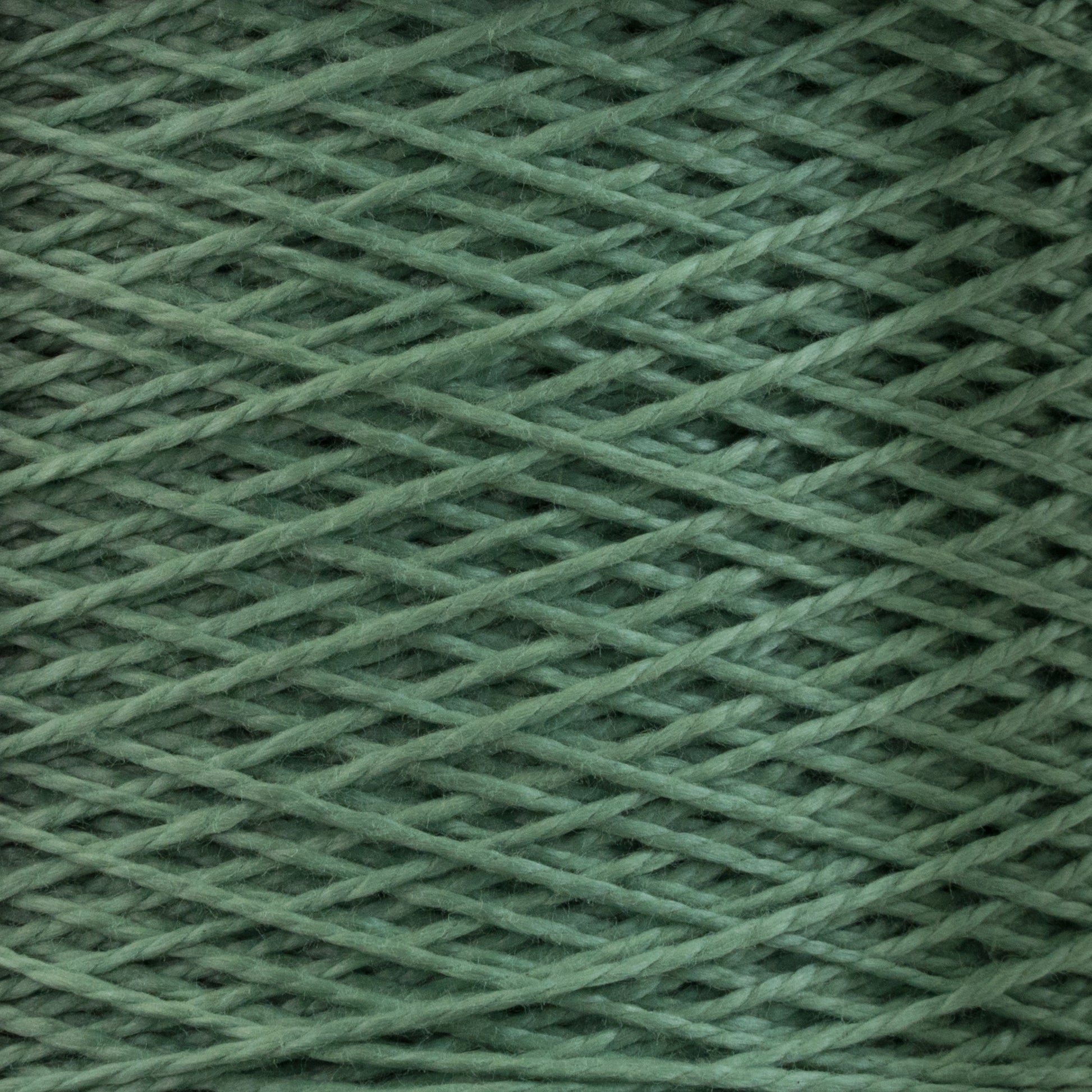 Close-up image of Supreme Corp's 5/2 Pearl Cotton Yarn in green, tightly wound and forming a crisscross pattern. The texture is smooth and the color uniform, showcasing the fine details and fibers of this mini-cone yarn—perfect for intricate weaving projects.