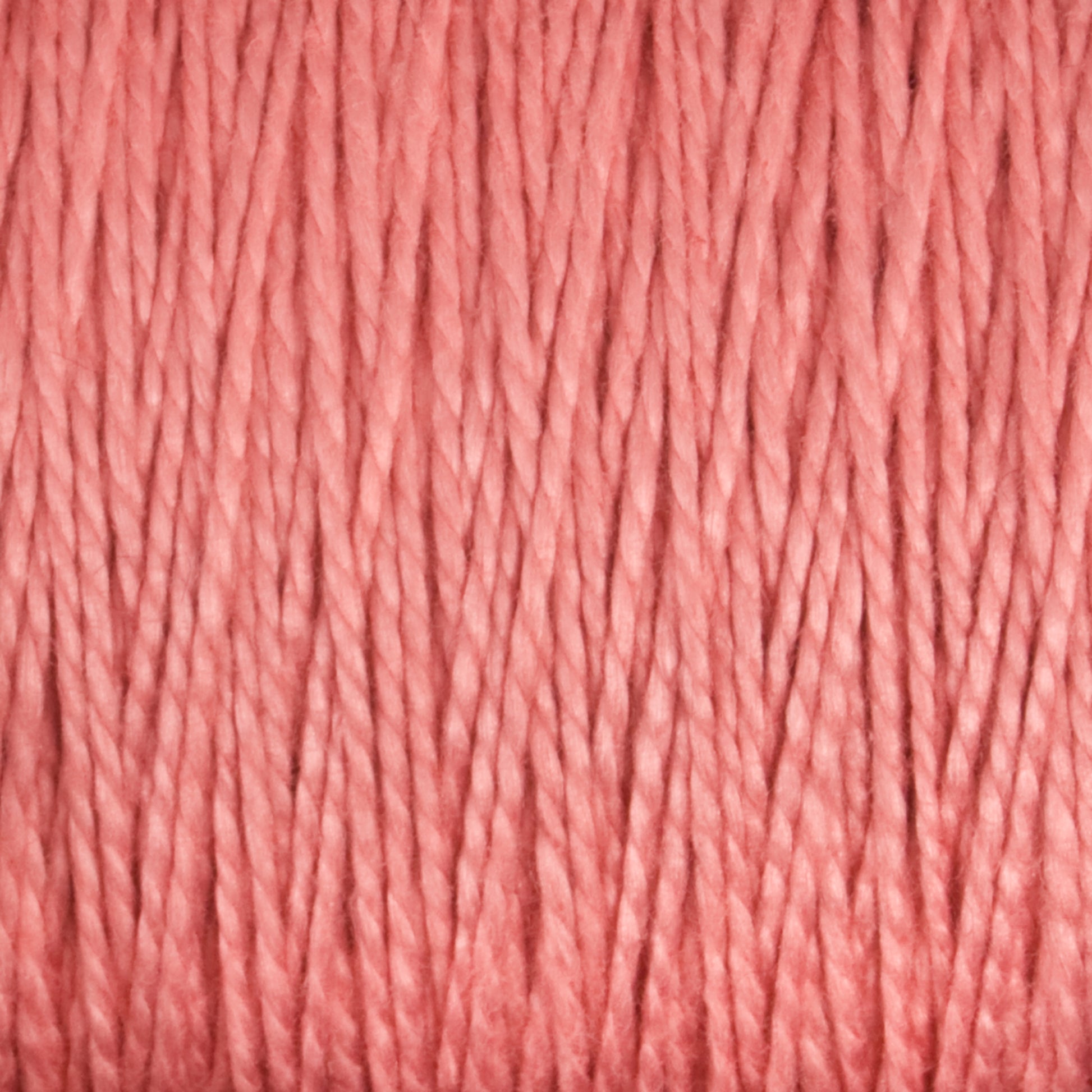 Close-up of Supreme Corp's 5/2 Pearl Cotton Yarn in Mini-cone, showcasing its textured fibers in a soft, muted coral or salmon pink shade. The tightly wound and parallel fibers form a uniform pattern with a subtle sheen—perfect for weaving projects.