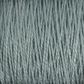 Close-up of tightly wound, light green 5/2 Pearl Cotton Yarn fibers from Supreme Corp. The texture appears soft and smooth, with visible twists and strands, ideal for weaving projects that require fine detail. This mercerized cotton yarn ensures a lustrous finish and durability. Available in a convenient mini-cone size.