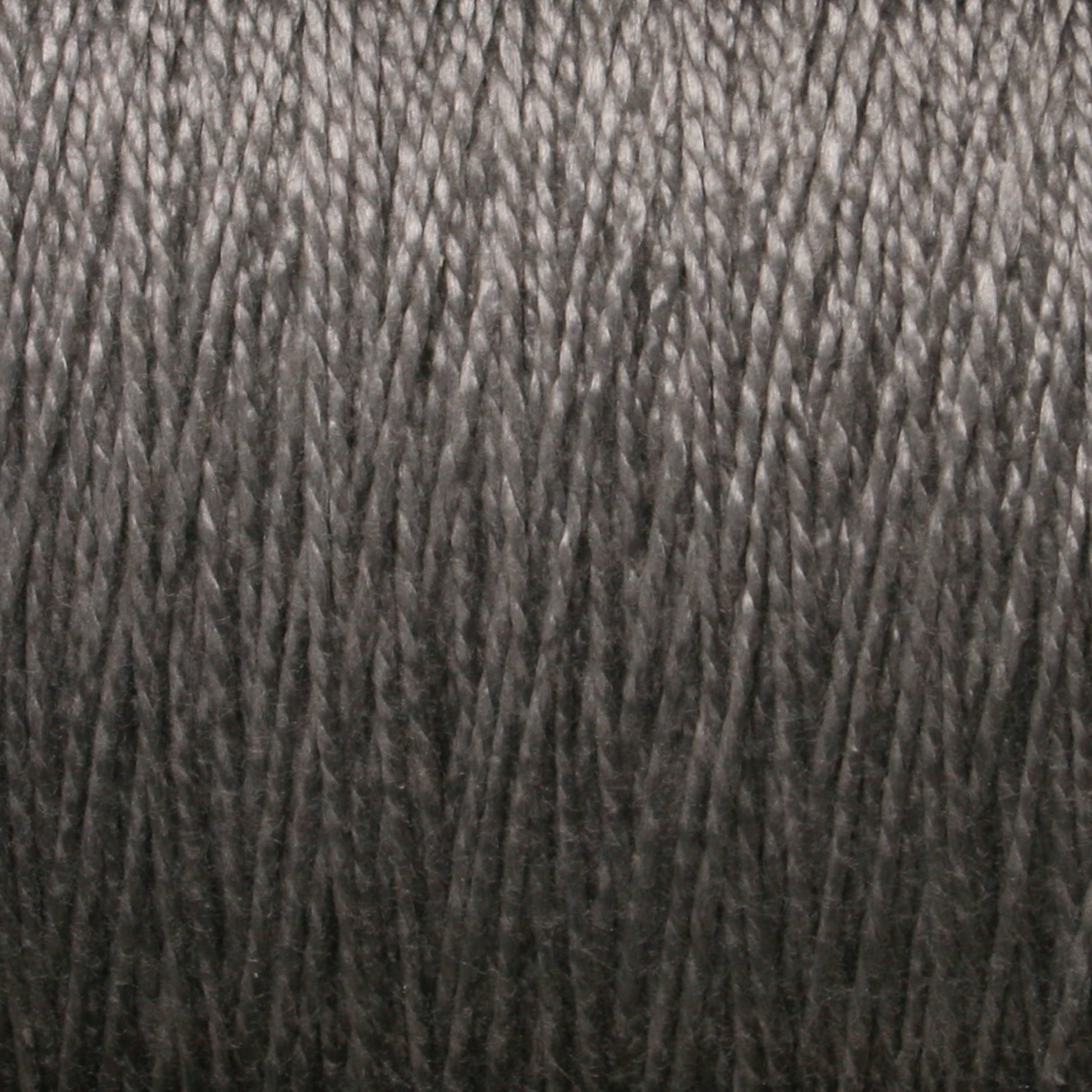 Close-up view of tightly wound, dark gray yarn showing the intricate strands and smooth texture of the thread. The silky, consistent nature of this 5/2 Pearl Cotton Yarn by Supreme Corp suggests it could be ideal for crafting or weaving projects.