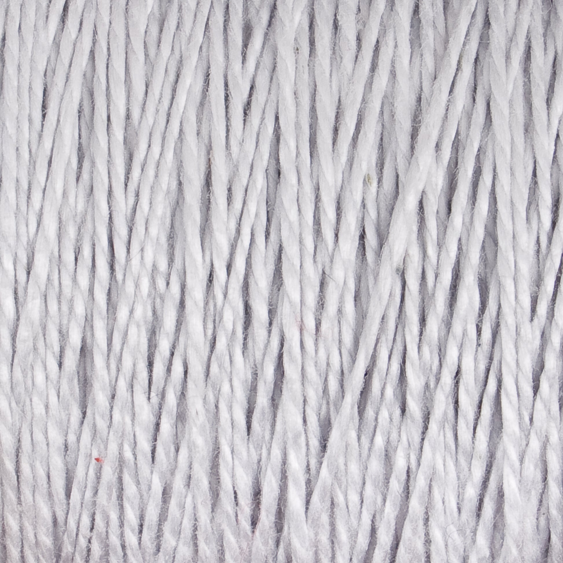 Close-up view of tightly wound, textured gray 10/2 Pearl Cotton Yarn from Supreme Corp. The image shows numerous individual strands, highlighting their fibrous, intertwined nature and creating a sense of depth and detail in the versatile yarn's surface as it forms on the large cone.