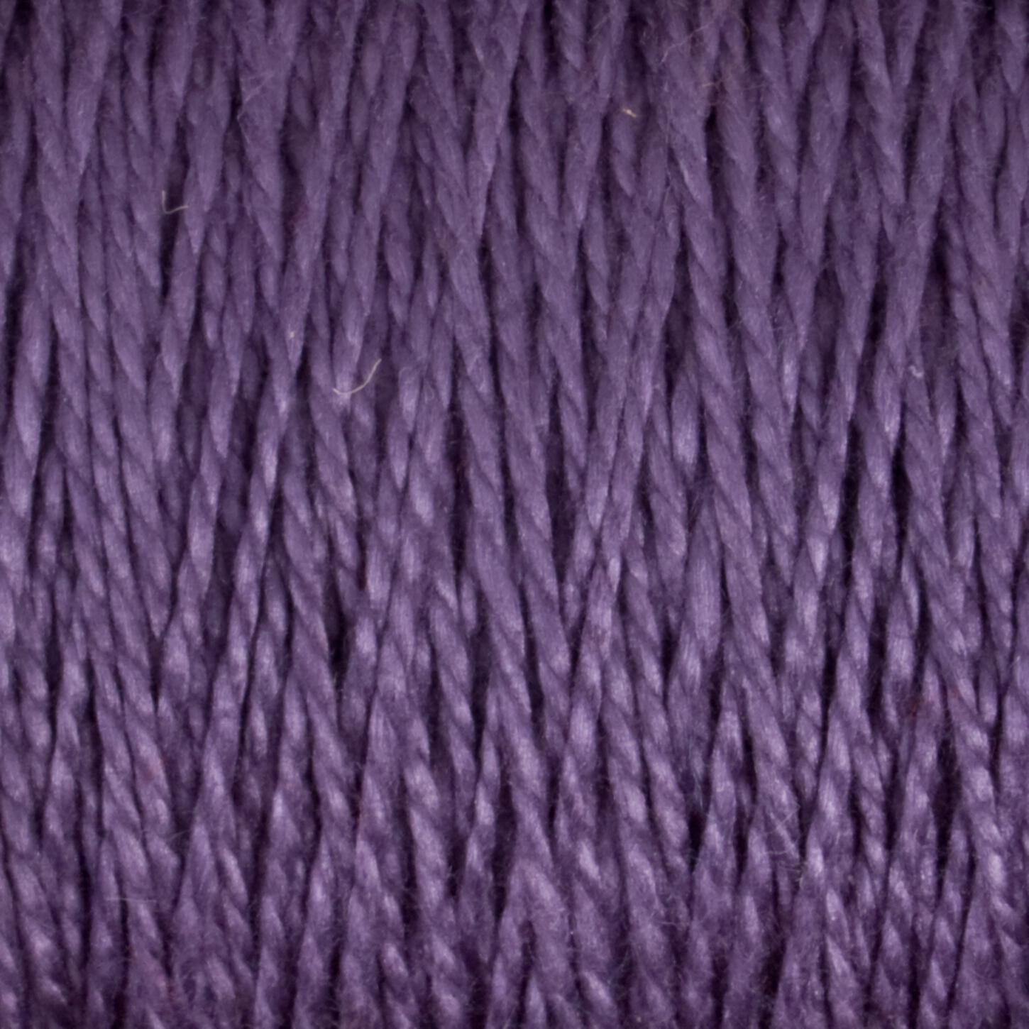 Close-up of 10/2 Pearl Cotton Yarn from Supreme Corp. The image shows tightly wound strands of versatile yarn, with a smooth texture and a consistent, rich purple color throughout. The Pearl Cotton fibers appear slightly glossy, reflecting light and giving the material a somewhat shiny appearance.