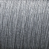 Close-up of a spool of silver-grey 10/2 Pearl Cotton Yarn from Supreme Corp., tightly wound with a smooth texture and uniform thickness. The fibers appear slightly shiny, adding a metallic sheen to the versatile yarn's overall appearance.