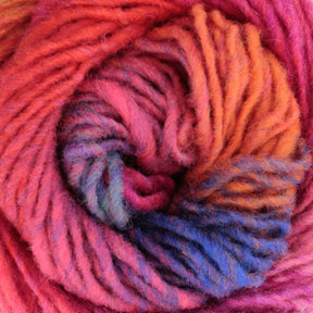 A close-up view of Kureyon by Noro in vibrant colors. The blended handspun yarn from Knitting Fever / Euro Yarns transitions from red to pink, orange, yellow, and blue, creating a mixed gradient with gradual color changes. The fibers are visibly soft and slightly fuzzy, wound in a spiral pattern.