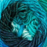 A close-up image of a ball of Kureyon by Noro from Knitting Fever / Euro Yarns showcasing tightly coiled strands of multicolored blended handspun yarn. The colors blend together in shades of turquoise, teal, dark blue, and patches of white, creating a visually textured and vibrant swirl pattern with gradual color changes.