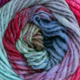 Close-up image of a skein of Kureyon by Noro from Knitting Fever / Euro Yarns, showcasing handspun shades of blue, red, and green intricately twisted together. The texture appears soft and slightly fuzzy with gradual color changes, creating a visually vibrant and cozy appearance.