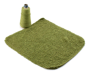 A spool of Halcyon Yarn's Washcloths / Dishcloths Sampler in green stands upright next to a square piece of knitted fabric in the same color. The textured, uneven surface of the fabric suggests intricate wash cloth patterns. The image is set against a plain white background, making it an ideal gift for knitters.