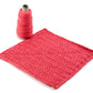 A pink crocheted square, ideal for washcloth patterns, is laid flat next to a spool of Halcyon Yarn Casco Bay Sport in matching pink. The thick, textured yarn beautifully enhances the lacy, intricate pattern of the square. Both items are perfectly displayed on a white background, showcasing the Washcloths/Dishcloths Sampler by Halcyon Yarn.