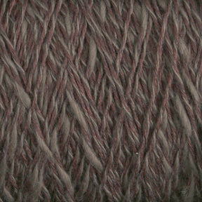 Close-up view of the Block Island Blend | Large Cone yarn with interwoven strands. The yarn, spun and dyed in Maine by Halcyon Yarn, features a mix of earthy tones, including shades of brown and gray, creating a natural and rustic appearance. The soft and slightly fuzzy texture gives it a cozy and warm look.