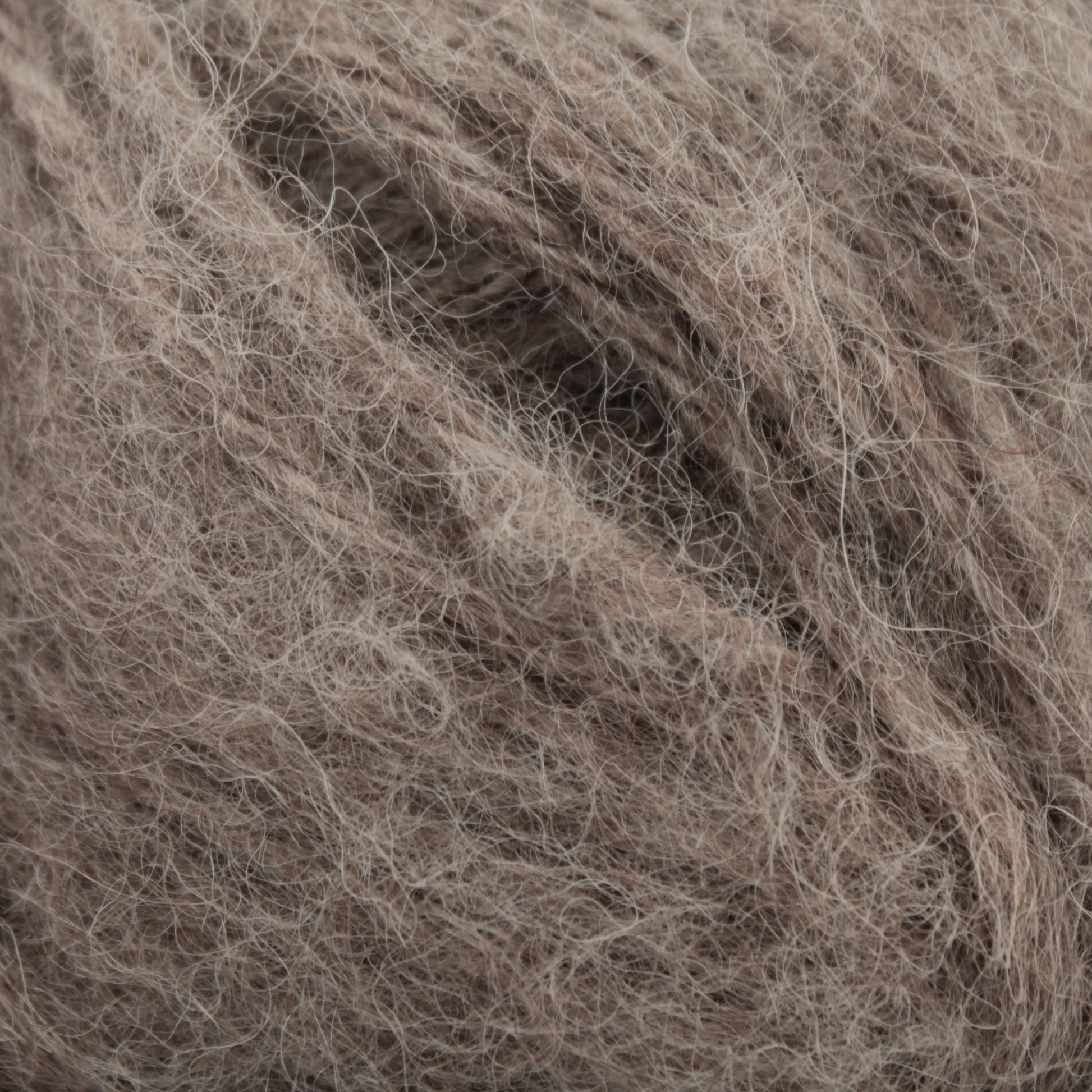 Close-up of Plymouth Yarn Co.'s Plymouth Baby Alpaca Brush, showing its soft, light brown fuzzy yarn with delicate fibers interwoven, creating a textured and fluffy appearance—perfect for crafting cozy alpaca sweaters.