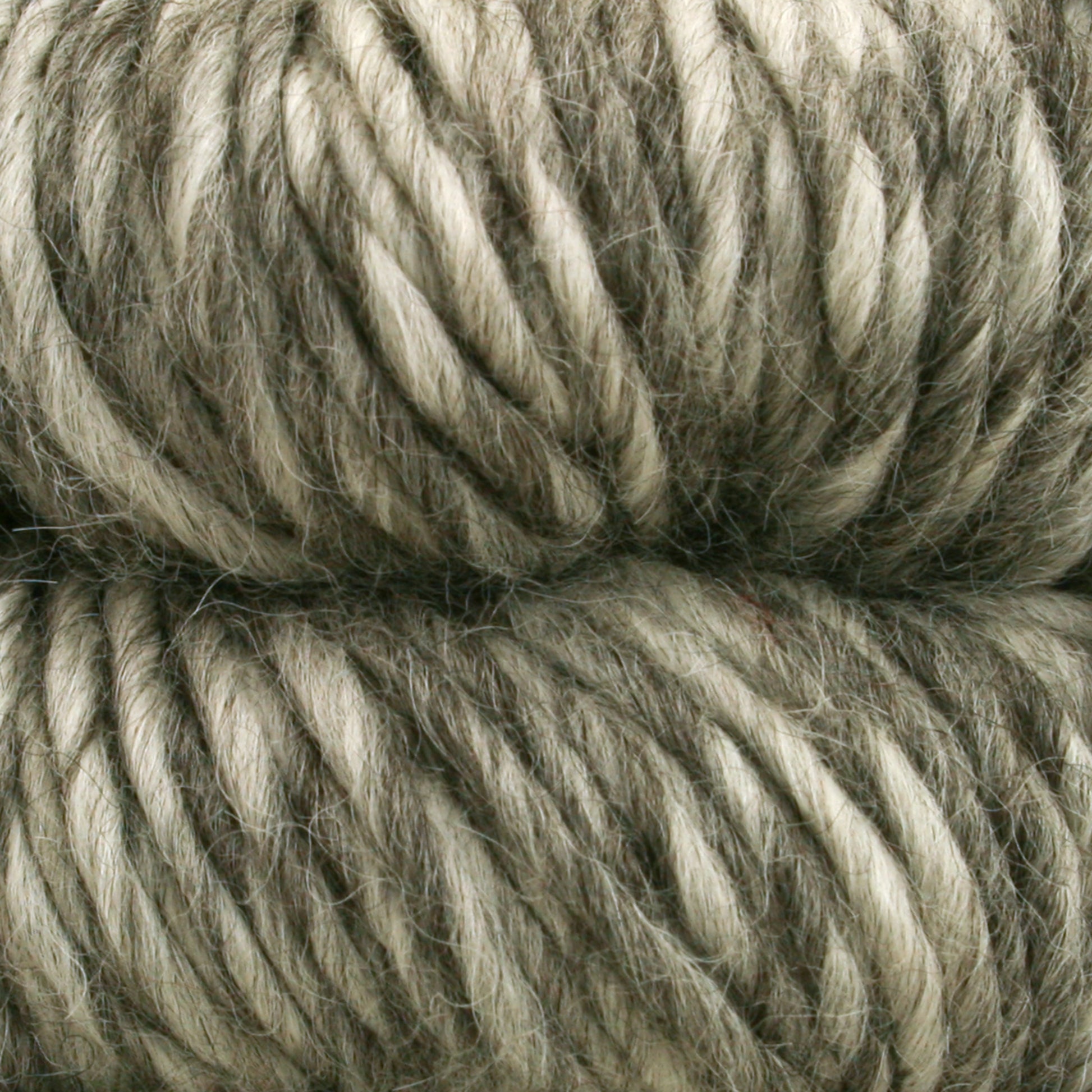 Close-up view of two skeins of thick, multi-textured yarn. The Cascade Eco Duo Baby Alpaca and Merino Yarn from Cascade Yarns appears soft and fluffy with shades of gray and off-white, twisted together to form chunky strands. The skeins are placed side by side, filling the frame with their luxurious natural colors.