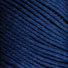 Close-up of Brown Sheep Cotton Fine, dark blue cotton yarn tightly wound into a ball. The texture of the yarn fibers is visible, showcasing a soft, slightly fuzzy surface perfect for machine knitters. The strands are neatly organized and evenly spaced.