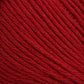 A close-up view of Brown Sheep's Cotton Fine yarn, showing the texture of the twisted threads. The red yarn appears soft and tightly wound, with slight variations in shading due to light reflections on the fibers, making it ideal for machine knitters.