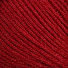 A close-up view of Brown Sheep's Cotton Fine yarn, showing the texture of the twisted threads. The red yarn appears soft and tightly wound, with slight variations in shading due to light reflections on the fibers, making it ideal for machine knitters.