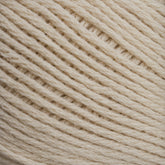 Close-up image of a ball of Cotton Fine yarn by Brown Sheep, showcasing the texture and tight weaving of the fibers. The yarn appears soft, with neatly arranged strands creating a diagonal pattern across the frame—a perfect choice for machine knitters.