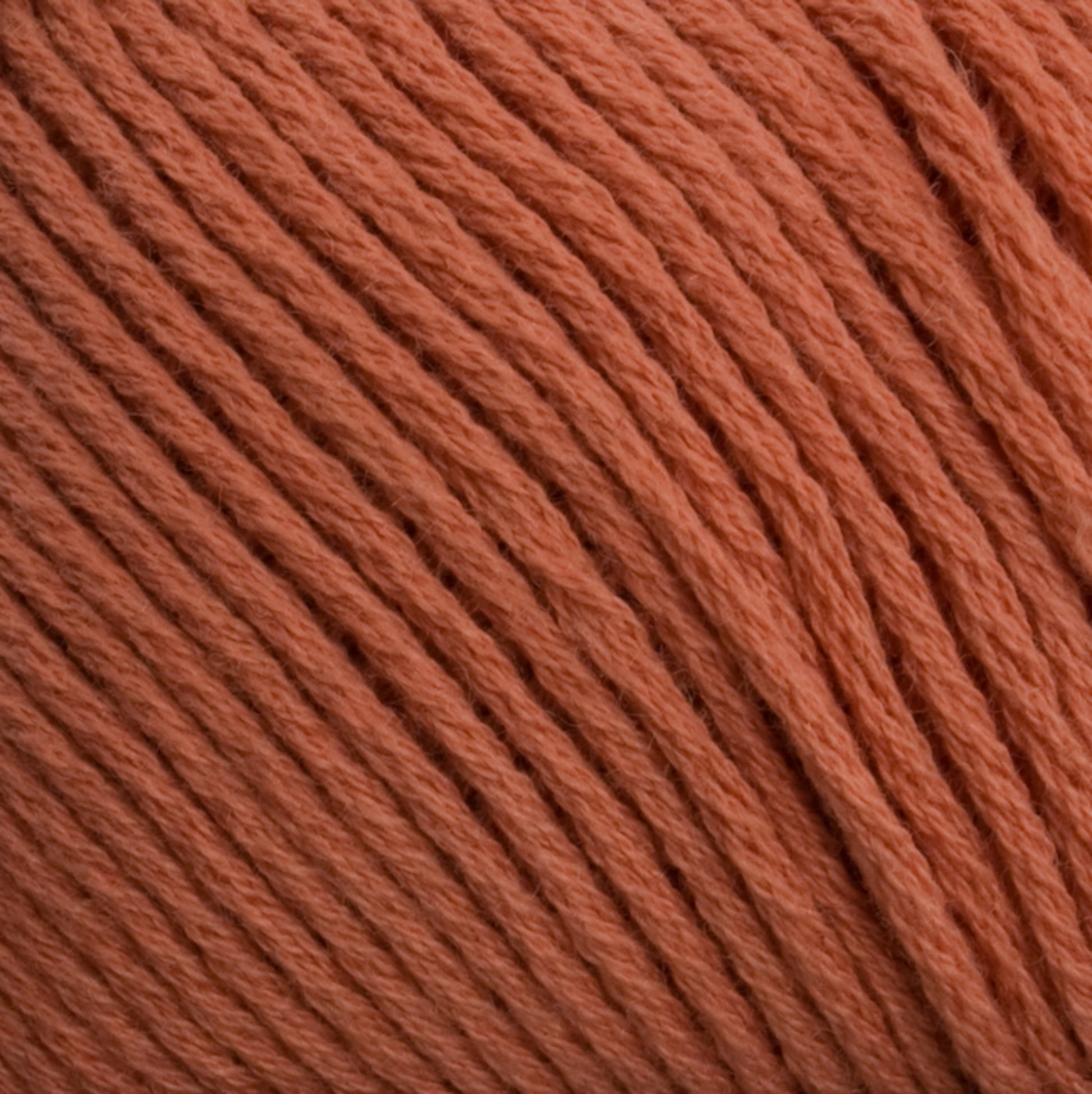 Close-up image of Brown Sheep's Cotton Fine yarn in orange, showcasing its tightly wound fibers. The texture is soft and the color is consistent throughout the strands, making it ideal for knitting, crocheting, or machine knitting.