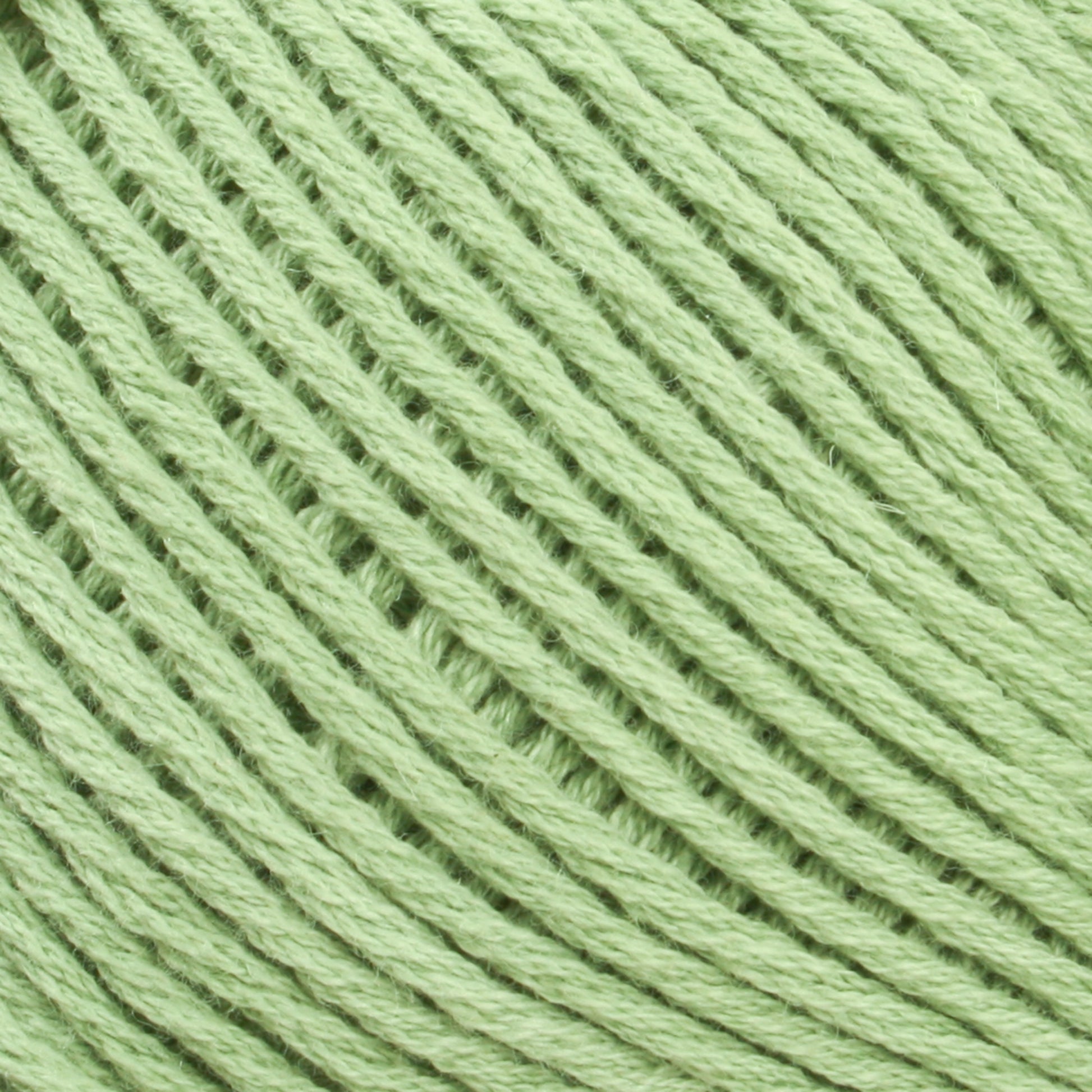 Close-up image of a spool of Brown Sheep's Cotton Fine green cotton yarn, showing the neatly wound threads in a repetitive, diagonal pattern. The texture appears soft and slightly fuzzy, ideal for machine knitters or weaving yarn projects.