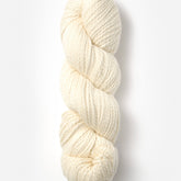 A single skein of Blue Sky Fibers Organic Cotton Worsted in off-white is coiled neatly against a plain white background. The texture of this worsted weight yarn from Blue Sky Fibers is soft, with a twisted appearance, making it perfect for baby knits or other knitting and crocheting projects.