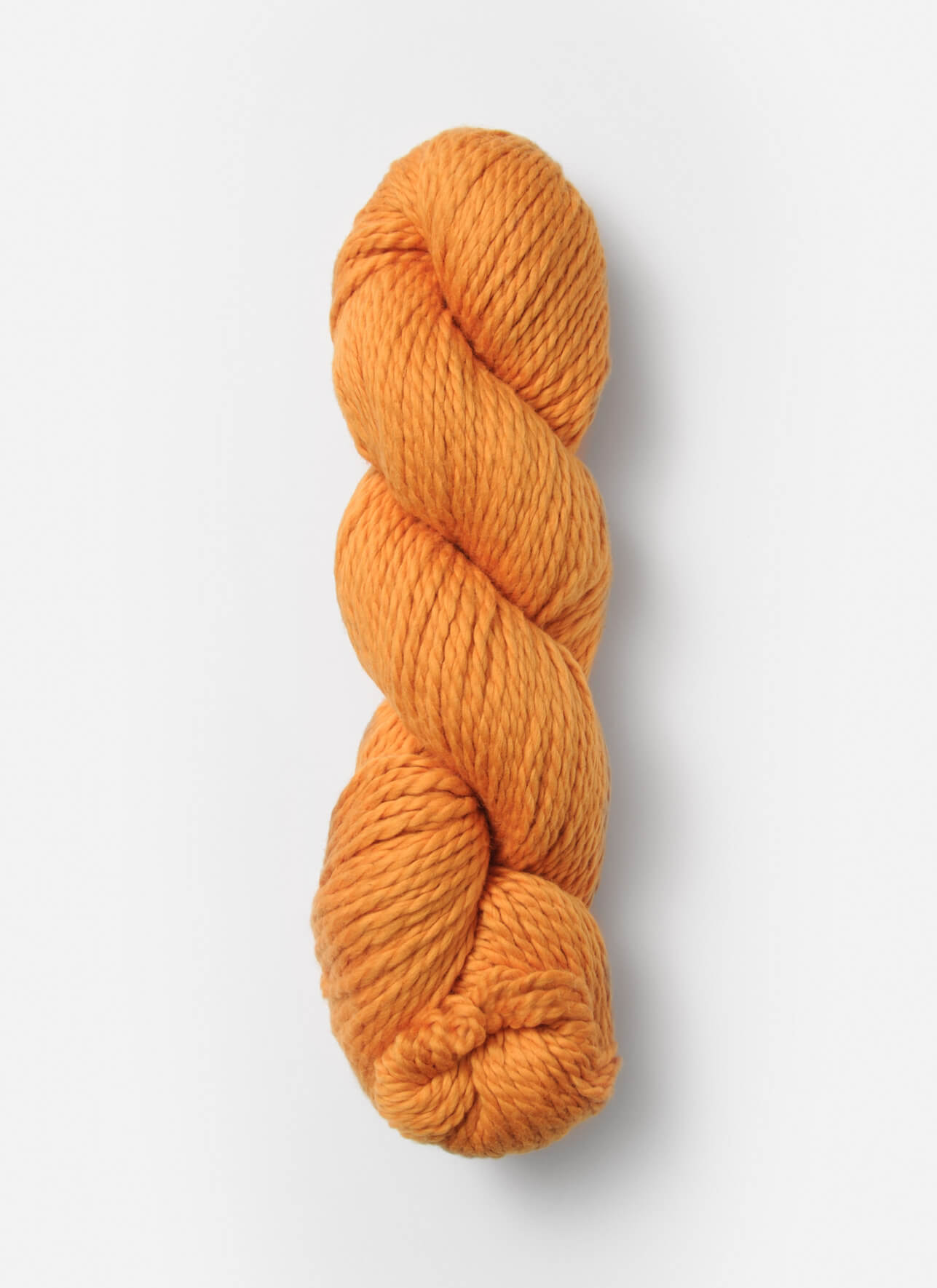 A skein of Blue Sky Fibers Organic Cotton Worsted yarn by Blue Sky Fibers is tightly wound in a spiral and displayed against a plain white background. The thick, orange yarn has a smooth, slightly glossy texture, and the fibers appear to be uniformly twisted together.