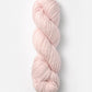 A skein of Blue Sky Fibers Organic Cotton Worsted in a soft pink hue is neatly twisted into a coil. This worsted weight yarn from Blue Sky Fibers looks thick and plush, making it ideal for knitting or crocheting cozy garments and baby knits. The plain white background highlights the gentle, soothing color of the yarn.