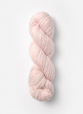 A skein of Blue Sky Fibers Organic Cotton Worsted in a soft pink hue is neatly twisted into a coil. This worsted weight yarn from Blue Sky Fibers looks thick and plush, making it ideal for knitting or crocheting cozy garments and baby knits. The plain white background highlights the gentle, soothing color of the yarn.