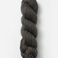 A skein of Blue Sky Fibers Organic Cotton Worsted in dark gray is displayed against a plain white background. This worsted weight yarn by Blue Sky Fibers, perfect for baby knits, is tightly twisted into a neat cylindrical shape.