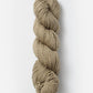 A neatly twisted skein of Blue Sky Fibers Organic Cotton Worsted yarn against a plain white background. The beige, worsted weight yarn from Blue Sky Fibers has a soft, slightly textured appearance, making it perfect for knitting or crocheting baby knits.