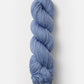 A single skein of Blue Sky Fibers Organic Cotton Worsted in chunky blue, neatly twisted into a tight coil, displayed against a clean white background. This worsted weight yarn from Blue Sky Fibers features a soft texture and a rich, consistent color throughout.