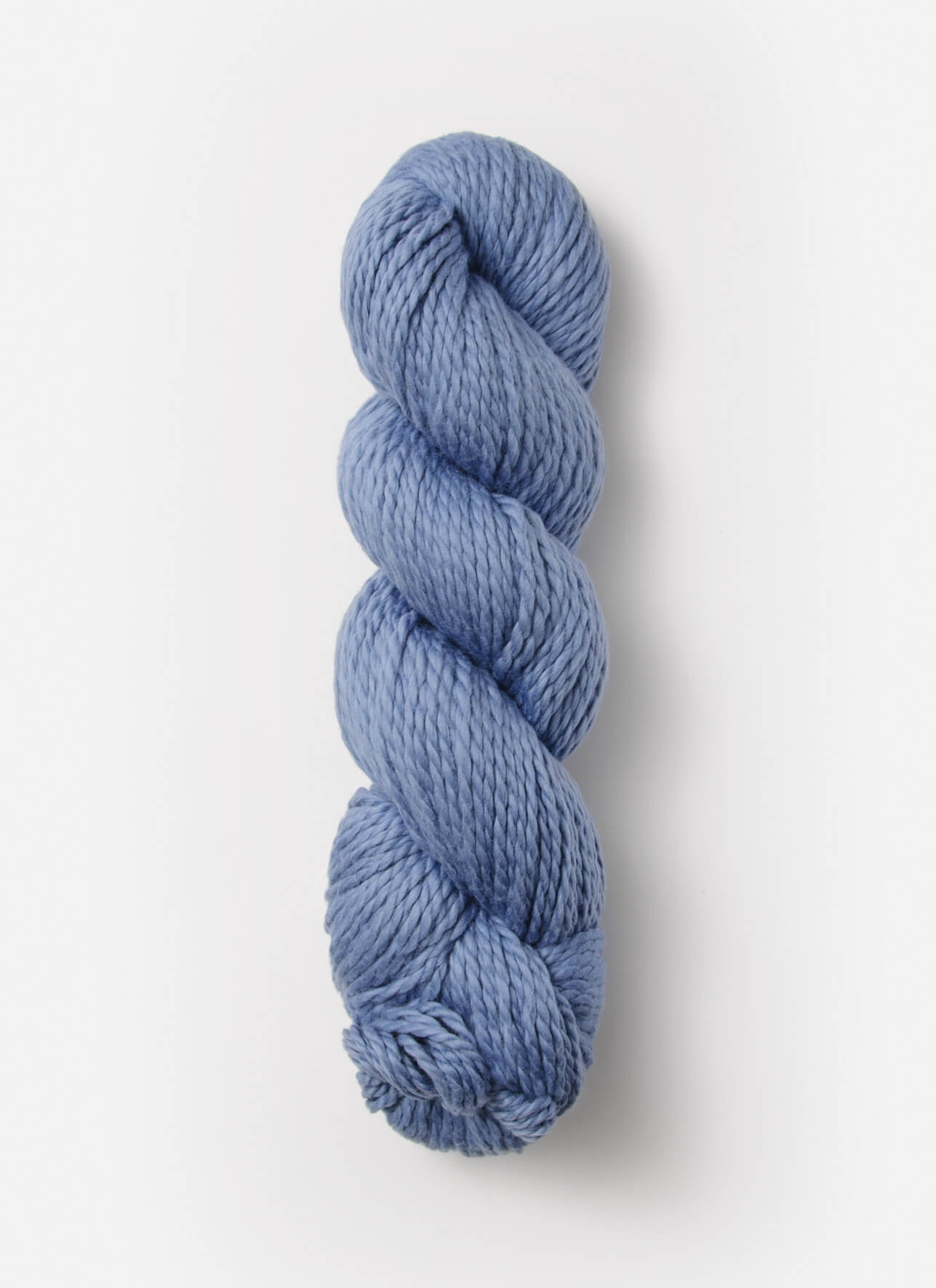 A single skein of Blue Sky Fibers Organic Cotton Worsted in chunky blue, neatly twisted into a tight coil, displayed against a clean white background. This worsted weight yarn from Blue Sky Fibers features a soft texture and a rich, consistent color throughout.