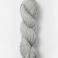 A neatly twisted skein of Blue Sky Fibers Organic Cotton Worsted in light gray is shown against a plain white background. The yarn appears thick and soft, suitable for knitting or crocheting projects, including cozy baby knits.