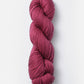 A skein of Blue Sky Fibers Organic Cotton Worsted yarn in a rich, burgundy color is displayed against a plain white background. The yarn appears soft and plush, making it perfect for baby knits or other cozy projects.