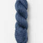 A skein of Blue Sky Fibers Organic Cotton Worsted in dark blue is neatly wound in a twisted bundle against a plain white background. The texture of the Blue Sky Fibers worsted weight yarn appears soft and slightly thick, making it ideal for knitting or crocheting projects, especially baby knits.