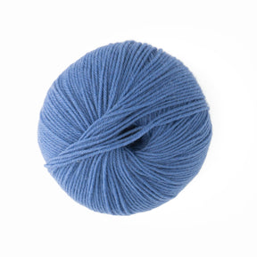 A skein of Baby Blatt by Anny Blatt, a light blue, 100% wool yarn from Essentially Felt Studio & Fine Yarn, is tightly wound into a round shape and shown against a white background. The fingering weight yarn appears soft and suitable for knitting or crochet projects.