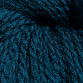 A close-up image of thick, dark teal Cascade Eco and Cascade Eco Plus Wool Yarn from Cascade Yarns showcases its soft and textured strands wound together. The fibers appear plush and densely packed, highlighting the yarn's fluffy and cozy nature.