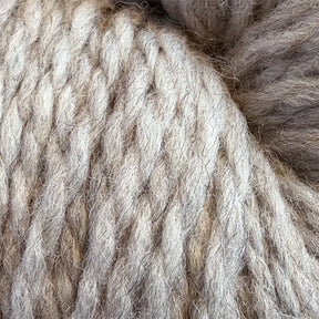 Close-up of light brown and beige strands from the Cascade Eco and Cascade Eco Plus Wool Yarn by Cascade Yarns. The thick, twisted fibers exhibit a soft, slightly fuzzy texture, making them ideal for felted knitting or crocheting. Made from Peruvian Highland wool, this yarn is perfect for your next sustainable project.