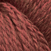 Close-up image of red Cascade Eco and Cascade Eco Plus Wool Yarn fibers intertwined in a textured and slightly fuzzy appearance. The eco yarn, from Cascade Yarns, features a rich, earthy red tone with subtle variations in color.