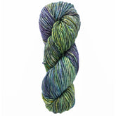 A skein of Malabrigo Mecha by Malabrigo Yarn, showcasing a stunning combination of green, blue, and purple shades, is tightly wound against a white backdrop. This exquisite superwash bulky yarn ensures both durability and vibrant color in every stitch.