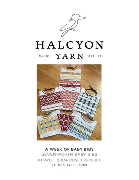 A set of seven handwoven baby bibs, each showcasing unique patterns and colors, is displayed on a wooden surface. Above the bibs is the Halcyon Yarn logo along with text explaining that these bibs are made using the Woven Baby Bib Pattern with Sweet Briar Rose Overshot on a four-shaft loom—an ideal stash buster project.