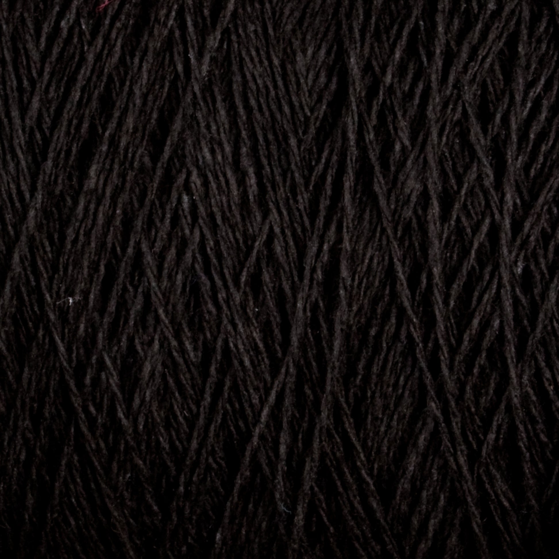 Close-up of Homestead 8/2 Cotton Yarn | Mini-cone by Supreme Corp. The tightly wound fibers create a dense, textured appearance with intertwining strands, highlighting the quality of this versatile black yarn.