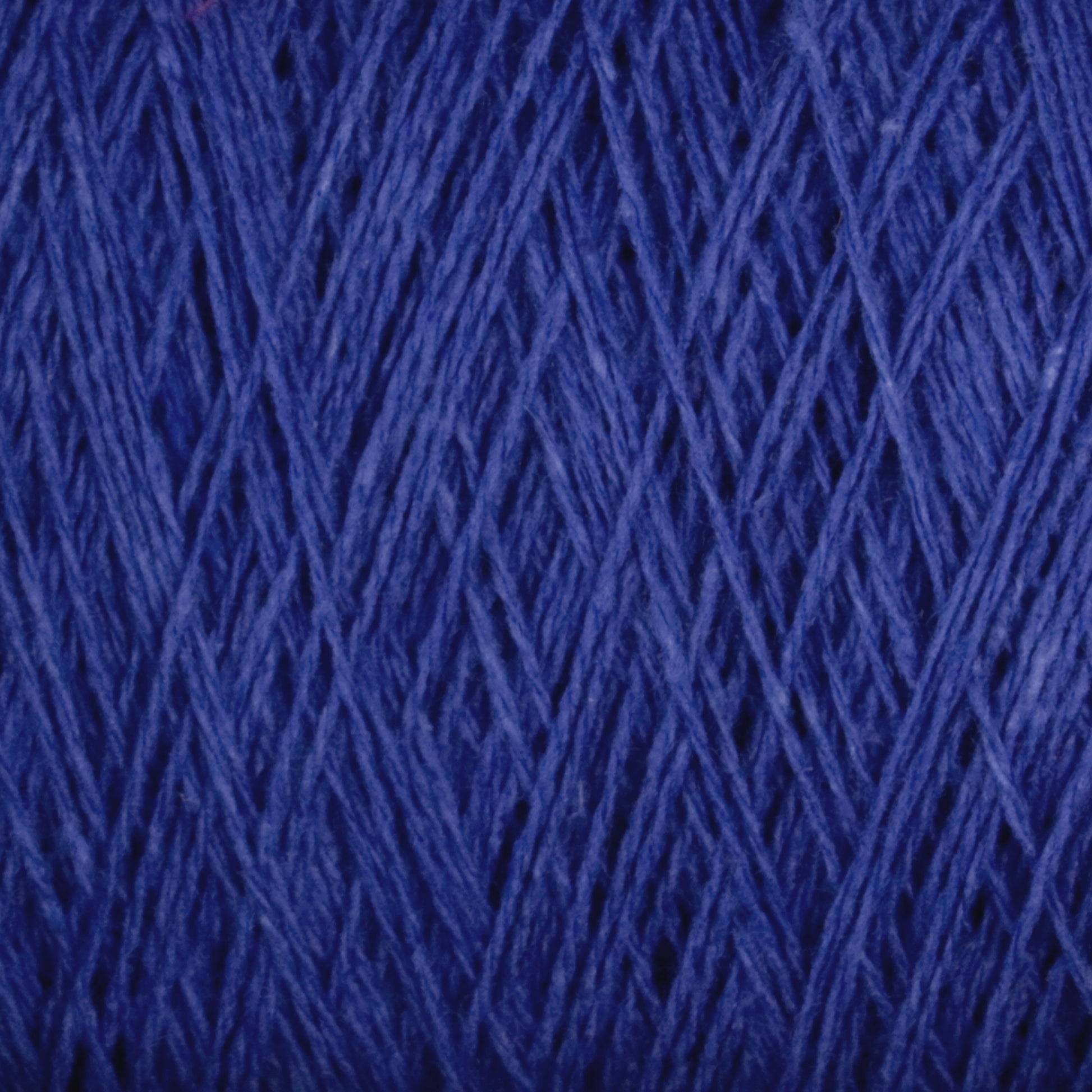 Close-up image of a ball of deep blue, Homestead 8/2 Cotton Yarn by Supreme Corp with tightly wound fibers. The texture is detailed, showing individual strands and a crisscrossing pattern.