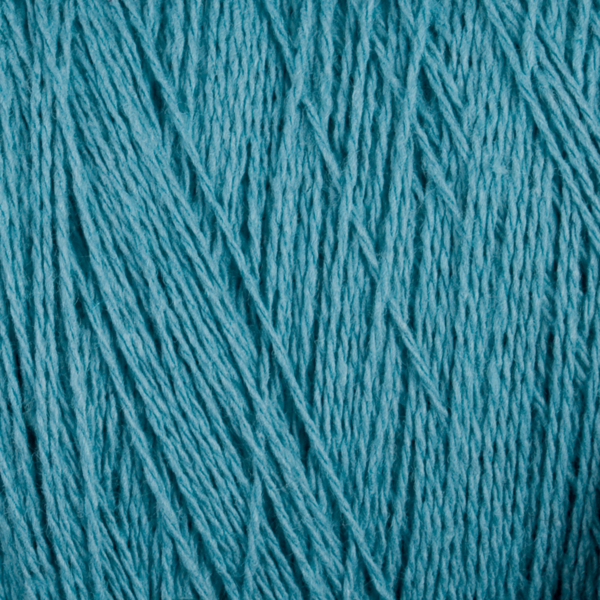 Close-up of turquoise-colored Homestead 8/2 Cotton Yarn | Mini-cone by Supreme Corp, showcasing its versatile nature with a tightly wound, textured surface where visible strands and fibers are intricately intertwined. The yarn boasts a smooth and slightly shiny appearance that highlights its soft and fine quality.