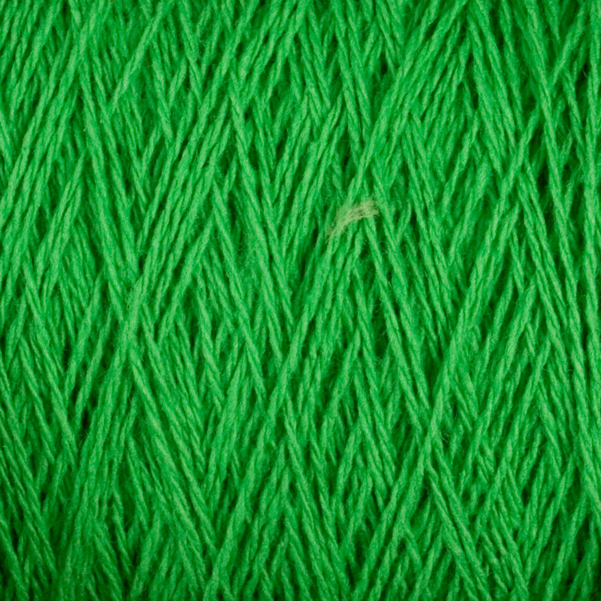 A close-up view of Supreme Corp's Homestead 8/2 Cotton Yarn on a mini-cone reveals bright green, machine-washable strands tightly wound together, creating a textured and detailed pattern. The fibers intersect and overlap, forming an intricate web of thread lines.