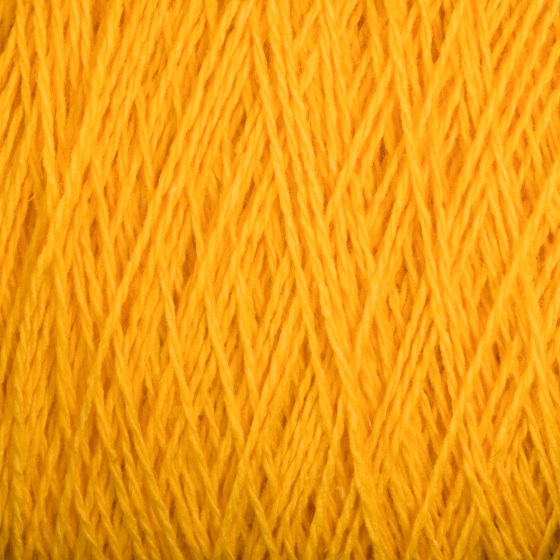 Close-up image of bright yellow Homestead 8/2 Cotton Yarn from Supreme Corp. The texture is detailed, showing the individual strands and fibers intertwined in a neat pattern. The image emphasizes the yarn's vibrant color and fibrous texture, typical of versatile materials like this machine-washable cotton yarn available in mini-cones.