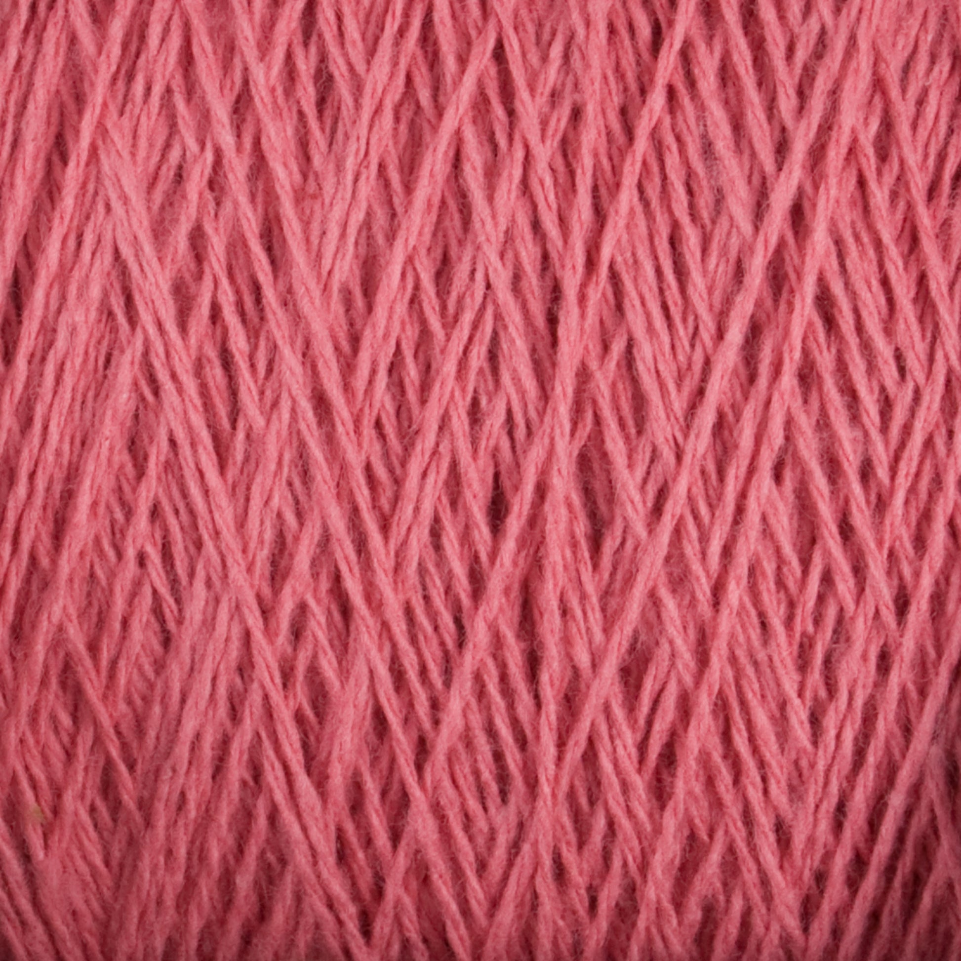 A close-up of Supreme Corp's Homestead 8/2 Cotton Yarn texture, showing intertwined strands of soft, fibrous thread. The yarn maintains a consistent color and thickness, resulting in a dense and intricate pattern perfect for knitting, crocheting, or other textile crafts. This weaving yarn comes in a large cone and is machine-washable for added convenience.