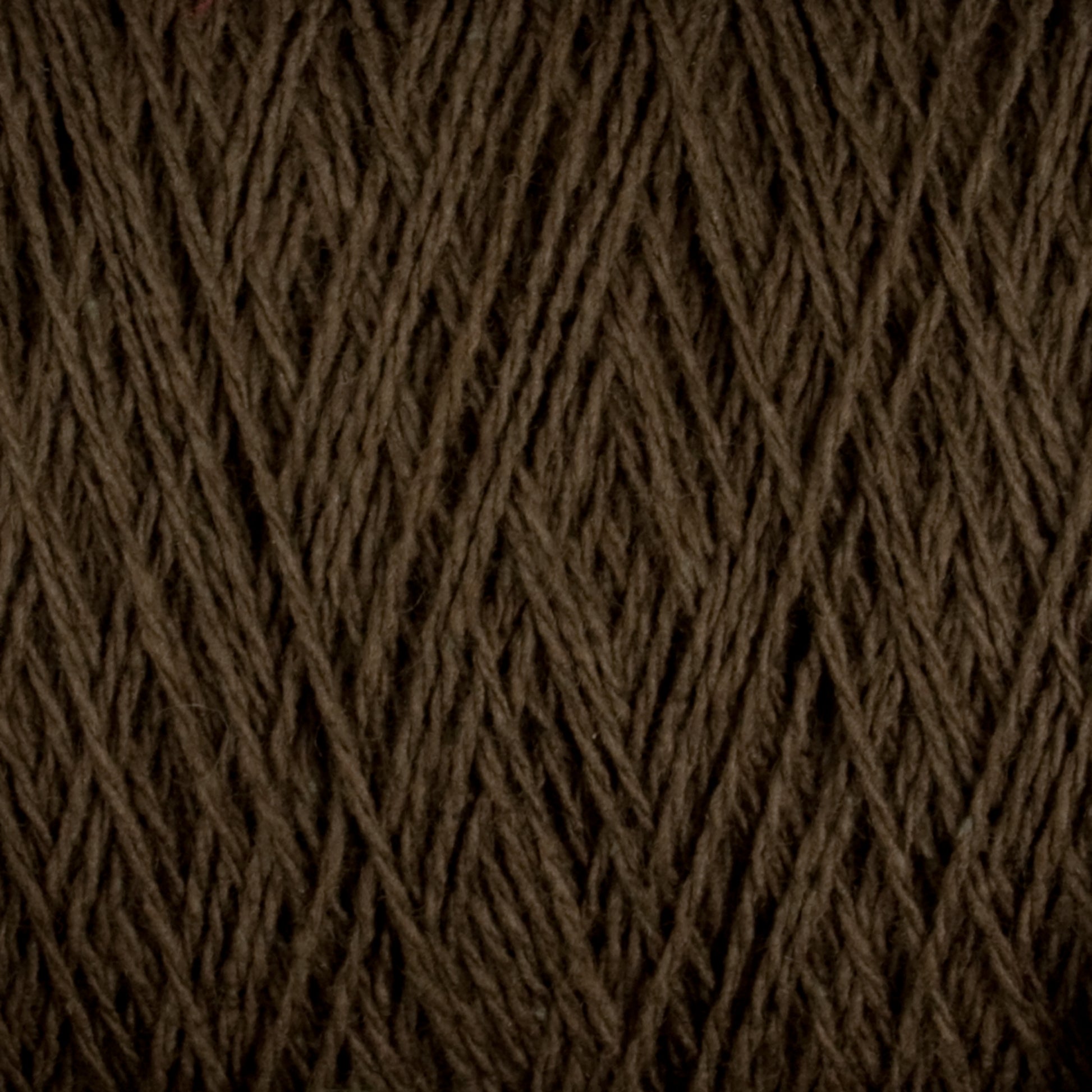 A close-up view of the Homestead 8/2 Cotton Yarn | Mini-cone by Supreme Corp, with its dark brown strands tightly wound in a crisscross pattern, showcases the texture and fibers of the material. This machine-washable yarn appears thick and slightly rough.