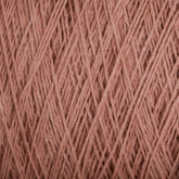 Close-up image of a spool of Homestead 8/2 Cotton Yarn | Mini-cone by Supreme Corp, showcasing the intricate patterns and textures of the pink fibers. The versatile yarn appears soft and slightly fuzzy, with light and shadow highlighting the individual strands.