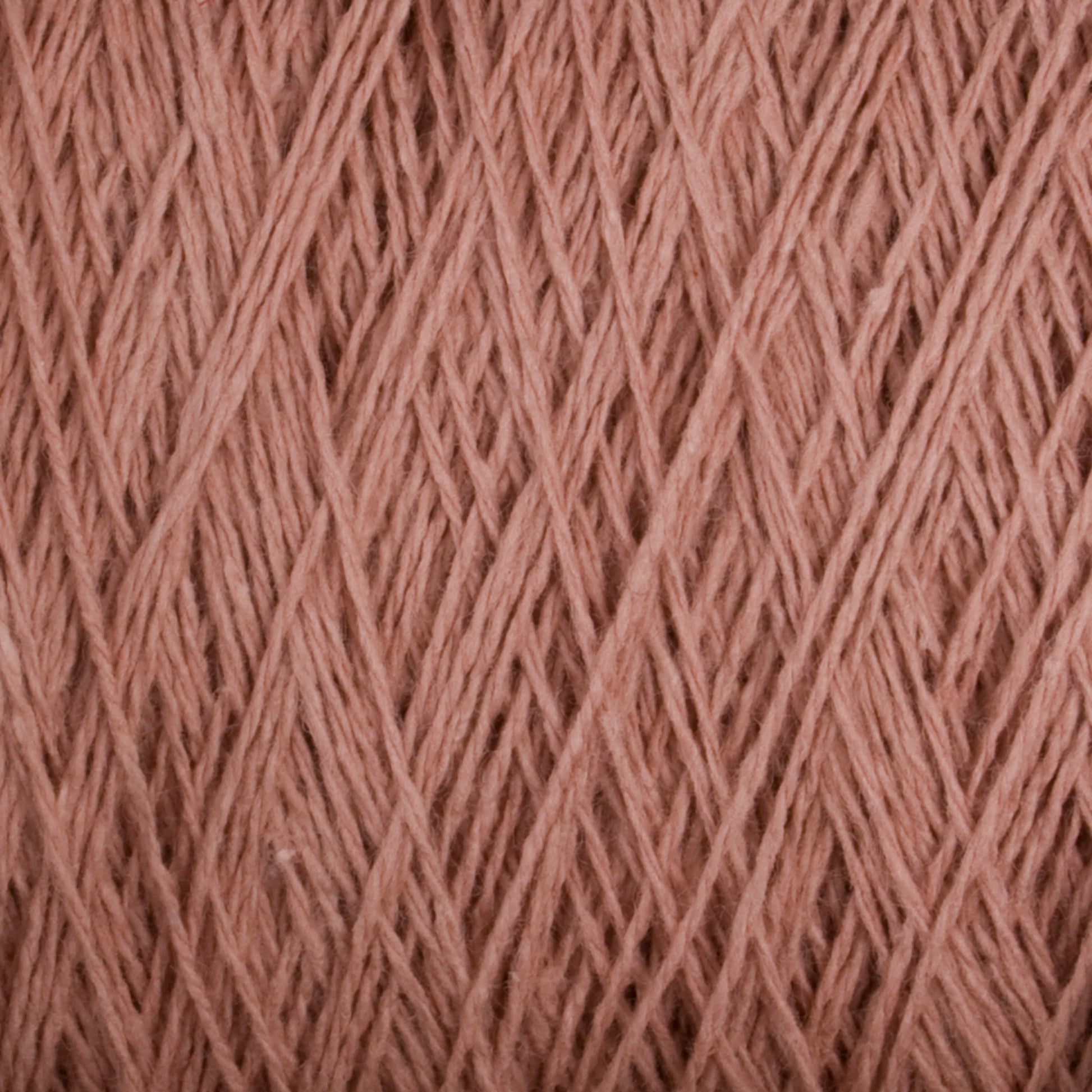 Close-up image of a spool of Homestead 8/2 Cotton Yarn | Mini-cone by Supreme Corp, showcasing the intricate patterns and textures of the pink fibers. The versatile yarn appears soft and slightly fuzzy, with light and shadow highlighting the individual strands.