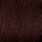 A close-up image of a spool of Supreme Corp's Homestead 8/2 Cotton Yarn in dark brown, showcasing the intricate texture of the fibers wound around the mini-cone. The intertwined threads form a pattern of diagonal lines, with subtle variations in tone and texture, demonstrating how this weaving yarn can be both functional and beautiful.