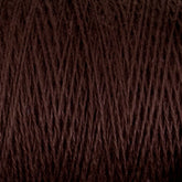 A close-up image of a spool of Supreme Corp's Homestead 8/2 Cotton Yarn in dark brown, showcasing the intricate texture of the fibers wound around the mini-cone. The intertwined threads form a pattern of diagonal lines, with subtle variations in tone and texture, demonstrating how this weaving yarn can be both functional and beautiful.